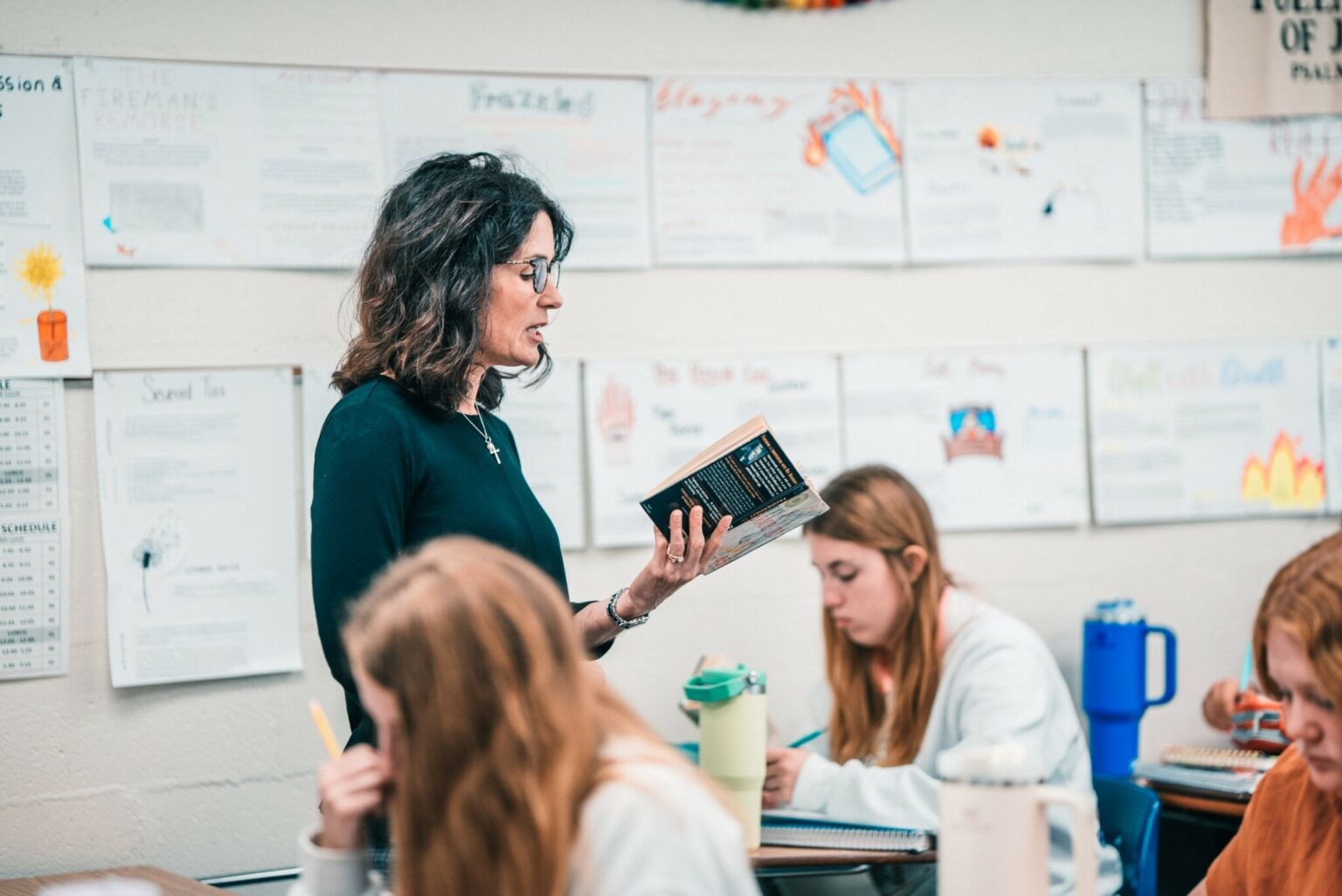 QND teacher reading to engaged students in a classroom at Quincy Notre Dame High School.