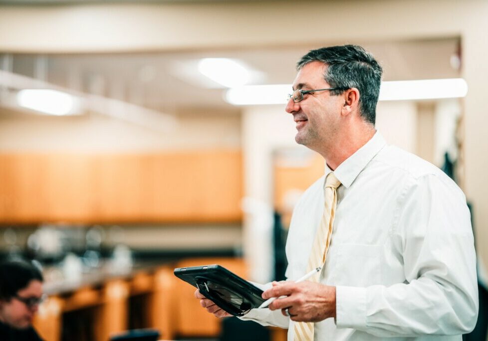 Job Opportunities at QND - QND teacher smiling while leading a lesson, fostering a positive learning environment at Quincy Notre Dame High School