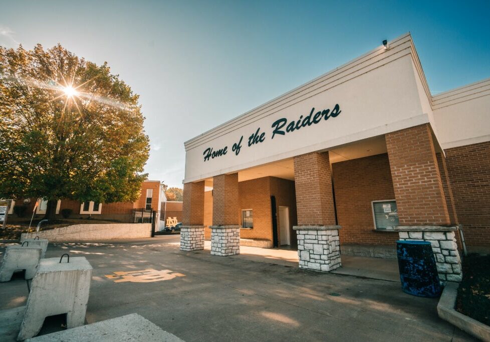 QND Board of Directors - Quincy Notre Dame High School athletic fields entrance with “Home of the Raiders” sign under a clear blue sky