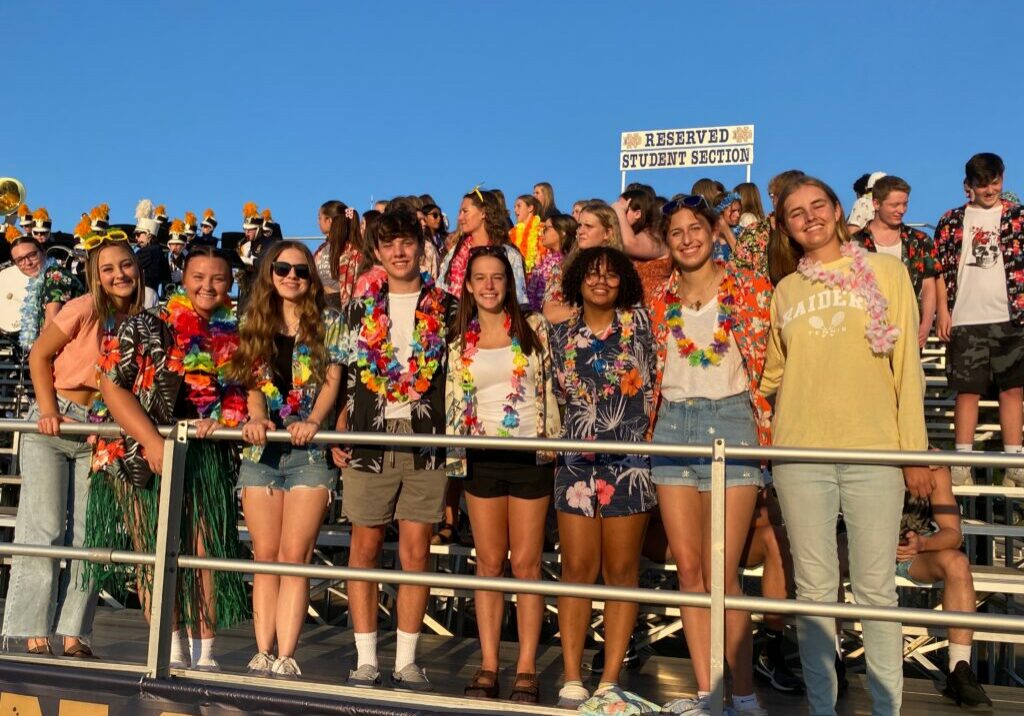 QND Logo & Branding Information - QND students dressed in tropical-themed outfits at a spirited school event in the reserved student section